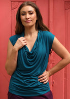 Woman wearing a cowl neck rayon teal cap sleeve top.