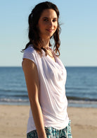 Woman on beach wearing a white cowl neck rayon top.