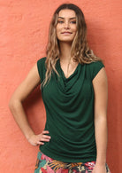 Woman wearing forest green cowl neck rayon top.