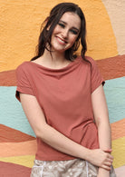 Woman with dark hair wearing a wide neck mod dusty rose stretch rayon boat neck top